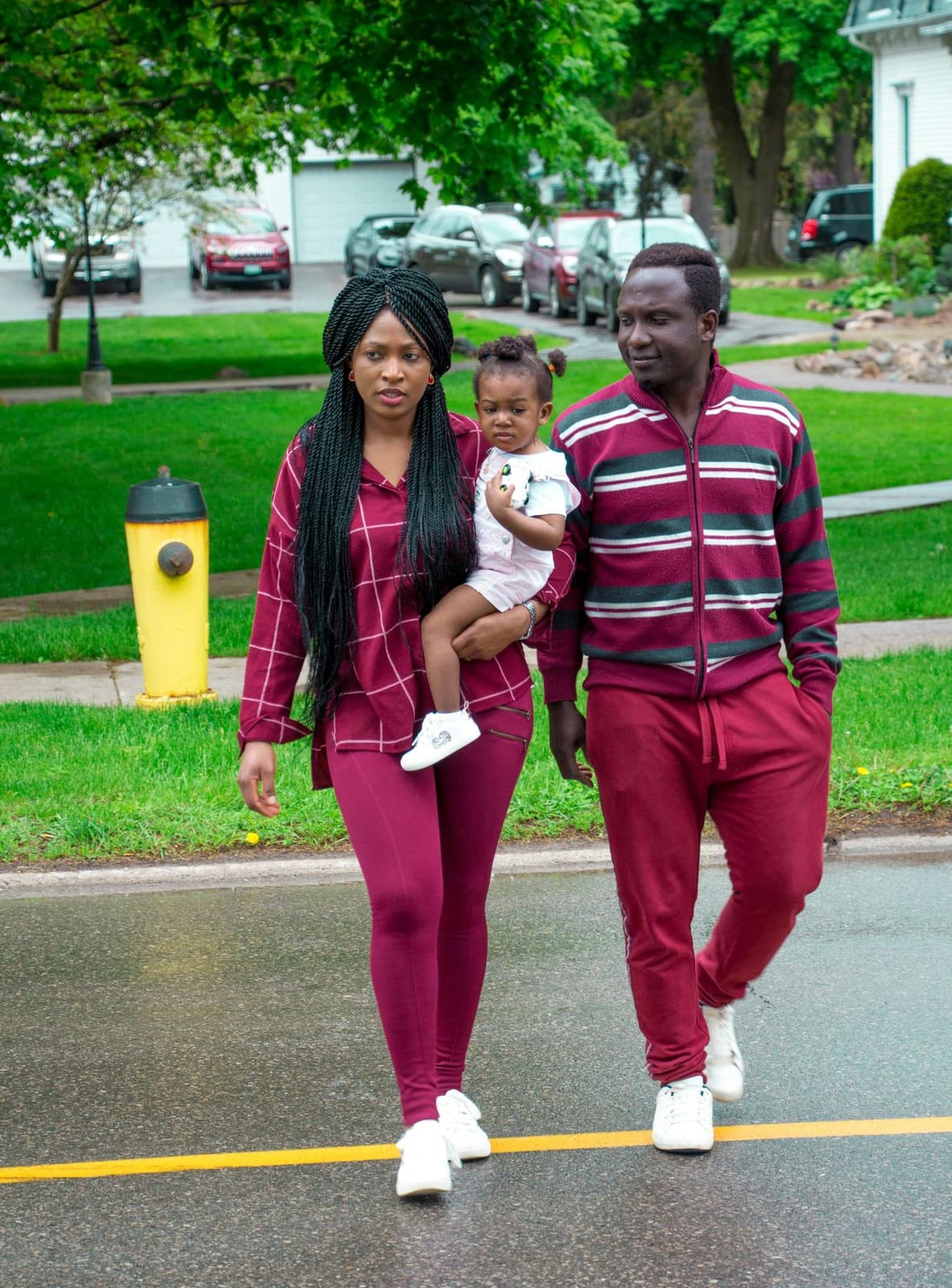 A young Black family walking together through a leafy park